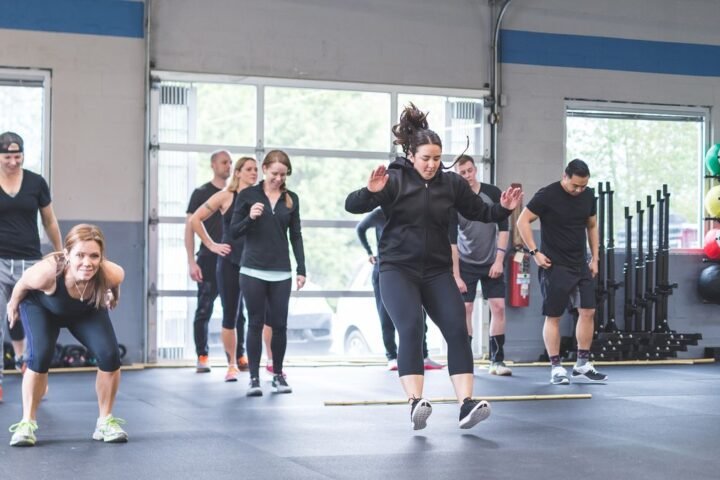 Women in an exercise class perform broad jumps