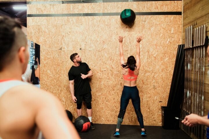 Woman performs wall ball exercise while three people look on