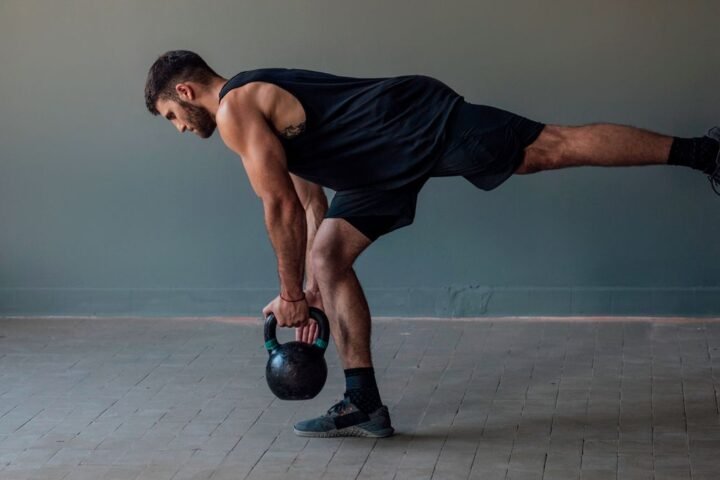 Man performs single-leg Romanian deadlift holding kettlebell