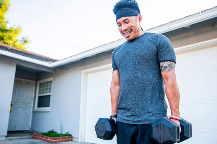 Man holding dumbbells outside a garage