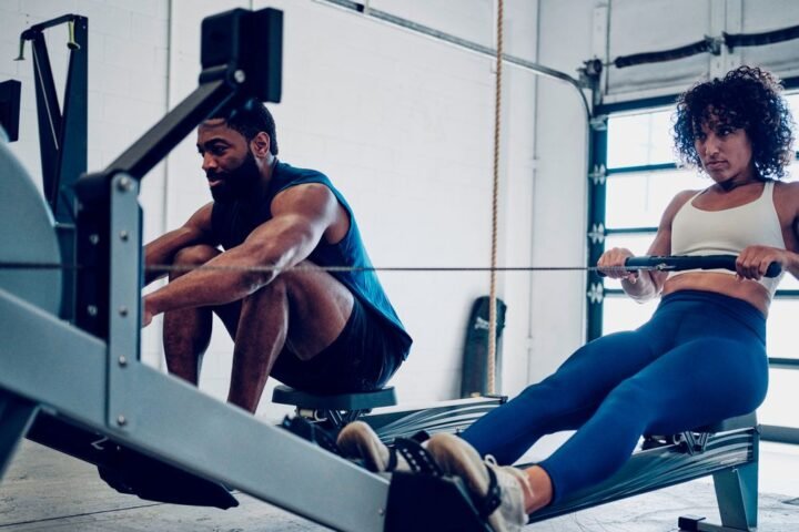 Woman and man row on indoor rowing machine