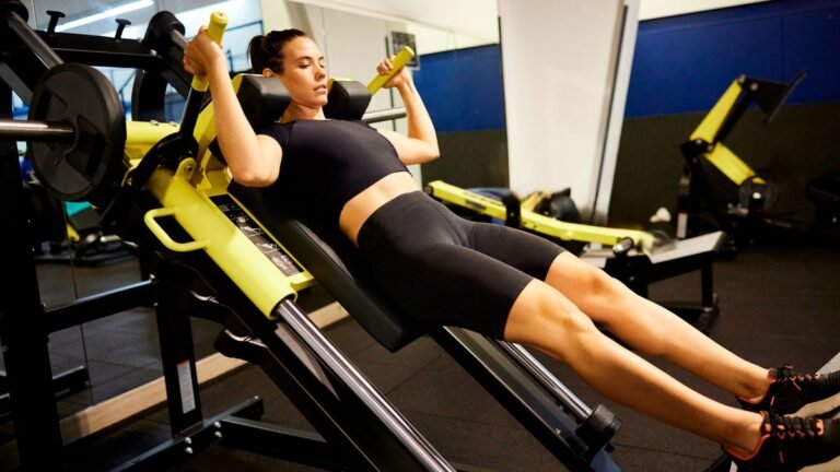 Woman using a hack squat machine