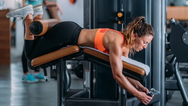 Woman performs lying leg curl on weights machine