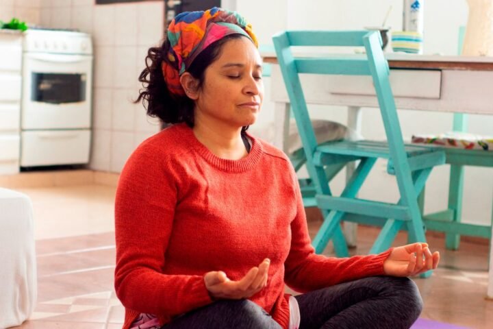 Woman sitting cross-legged on floor with hands resting on knees, palms raised